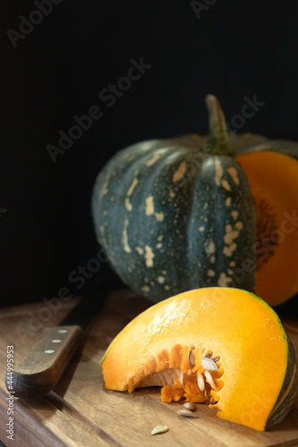 A pumpkin on a cuttting board with a slice cut. photo