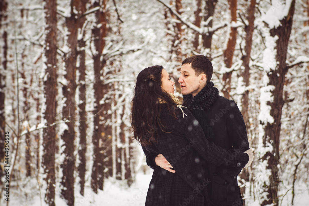 A guy and a girl in warm clothes and scarves on a walk in the snowy weather A guy and a girl in warm clothes and scarves on a walk in the snowy weather