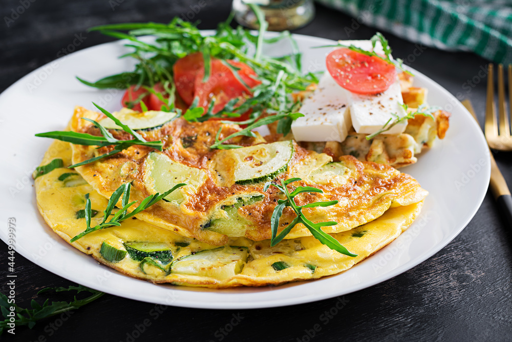 Omelette with zucchini, green herbs and sandwich with feta cheese on plate. Frittata - italian omelet. Omelette with zucchini, green herbs and sandwich with feta cheese on plate. Frittata - italian omelet.