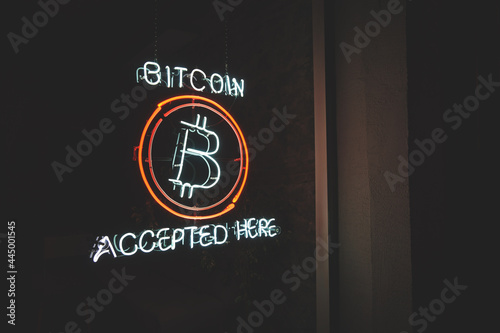 Bitcoin accepted here cryptocurrency led neon sign in a window of small business at night with copy space