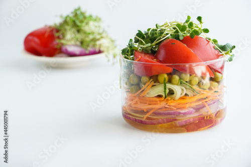A snack of raw vegetables in a glass. Bright vegetables on a white background