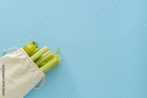 Delivery healthy food background. Vegan vegetarian food in eco cotton bag vegetables on blue background.Grocery shopping food supermarket and clean eating concept.Top view.Place for text