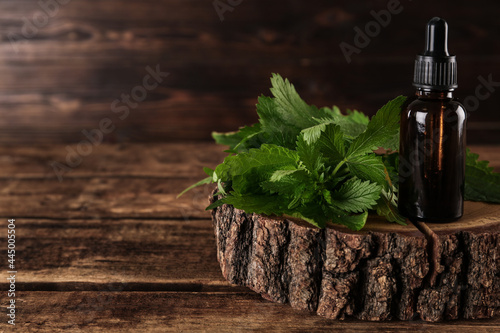 Schilderij op canvas Glass bottle of nettle oil with dropper and leaves on wooden table
