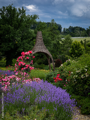 A wicker gazebo in the garden, surrounded with blooming flowers.  photo