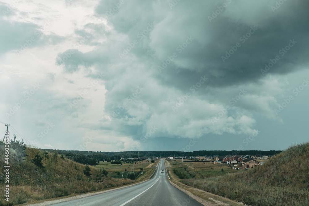 asphalt track road with a stormy dark sky background. empty track with black clouds