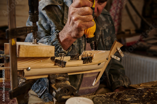 Craftsman sticking wooden details on a sailboat in his own workshop. Carpenter in action, lifestyles, hobby concepts
