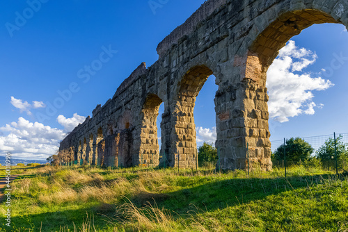 Park of the Aqueducts Rome, the imposing arches of the Claudio with blue sky and clouds and shadows reflected on the lawn. Archaeological area water system of ancient Rome. Via Appia Regional Park. photo