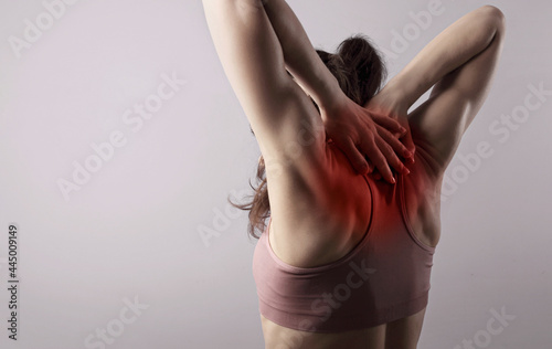 Attractive muscular female model doing stretching excecise on posture corrector with highlighted in red the spine and neck. Lock spine and neck exersice. Back view