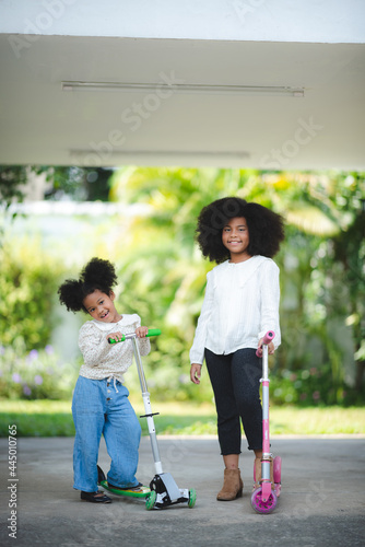 afro african american kid  portrait photo of sibing with scooter  child outdoor activity  brother and sister playing together  happy and smling face. family lifestyle concept.