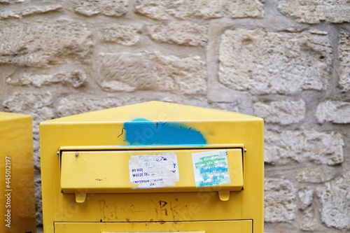 Closeup shot of a yellow postal box top detail attached to stone wall photo