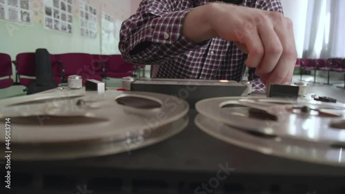 Male disc jockey presses buttons on reel to reel tape recorder at school retro disco. Vintage Tape Recorder. Old school concept. Popular Disco Trends 60s, 70s, 80s, 90s. On a plank floor.