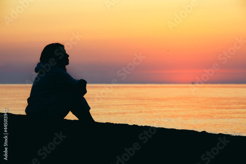 young woman sitting at sea beach looking on sunrise