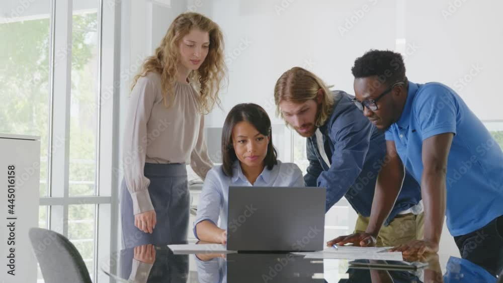 Group of young confident business people analyzing data using computer