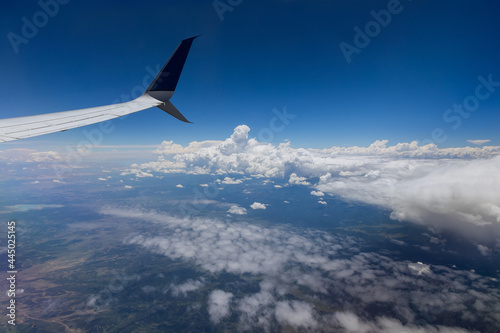 Airplane wing view out of the window on the cloudy sky the earth background