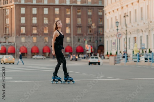 Wallpaper Mural Full length shot of slim dark haired woman rollerblades on asphalt road dresed in black sportsclothes enjoys outdoor activities exercises for healthy and strong body. Sport and hobby concept Torontodigital.ca