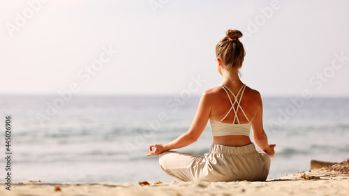 Calm woman meditating on beach at sunset
