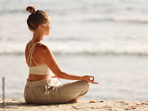 Calm woman meditating on beach at sunset