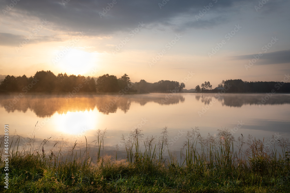 Beautiful sunrise at lake surrounded by forest in Krasnobród, Roztocze, Poland.