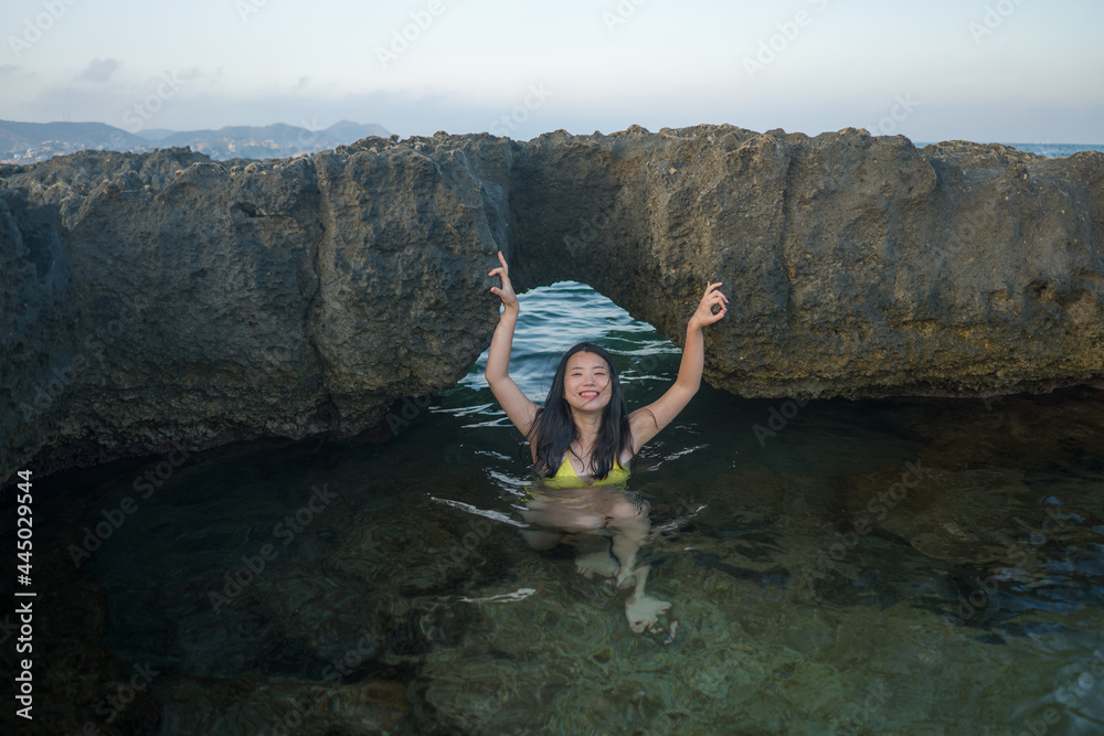 young happy and attractive Asian woman in the sea - cheerful and carefree Japanese girl playful in the water during Summer holidays trip in beautiful tropical island