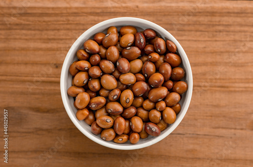 Beans in a Ceramic Bowl. These nutritious legumes are high in protein and fiber. The image is a cut out, isolated on a wood background