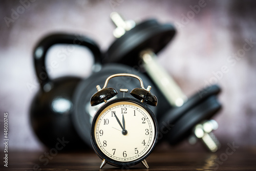 vintage alarm clock in fron of dummbell and kettlebell photo