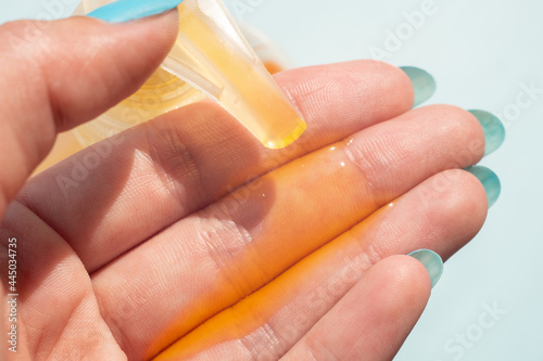 Female hand uses orange liquid soap with a dispenser