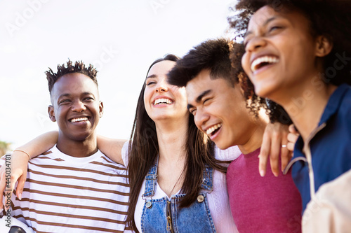 United multiethnic friends laughing and having fun together outdoors - Young adult group of funny people celebrating and hanging out - Summer holidays and college students concept - Focus on african