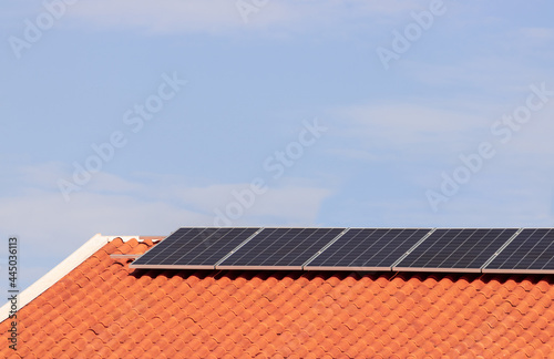 Solar photovoltaic panels on a roof at sunset. Clean energy modern house or company concept image. Space for text.