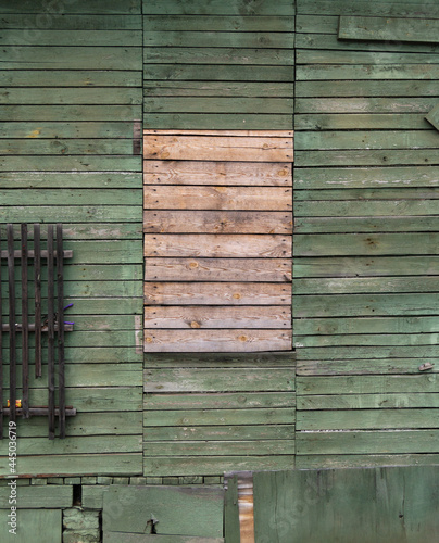 wooden green wall with boarded up window.