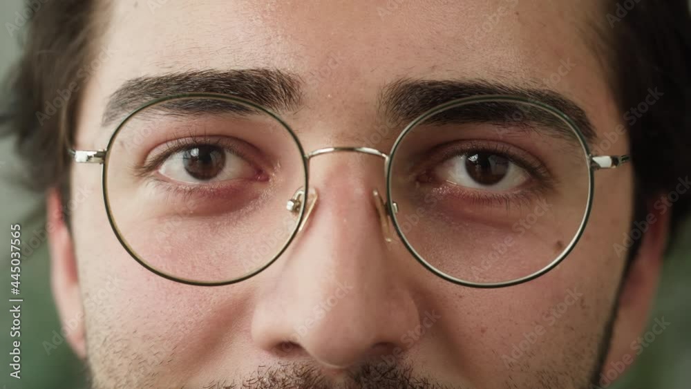 Brown eyes close-up, male face, young man wearing circle glasses portrait, guy with beard looking in camera closeup. Ophthalmology and vision concept. Brown eyes close-up, male face, young man wearing circle glasses portrait, guy with beard looking in camera closeup. Ophthalmology and vision concept.