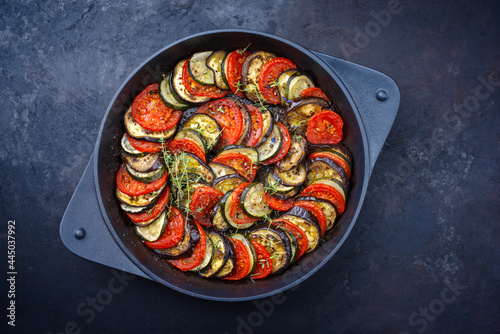 Modern style traditional French ratatouille with tomatoes, eggplant and zucchini served as top view in a rustic cast-iron skillet with copy space