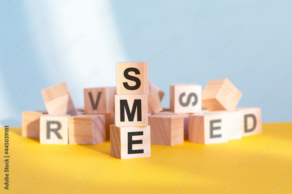 SME written on wooden cubes, yellow background SME written on wooden cubes, yellow background