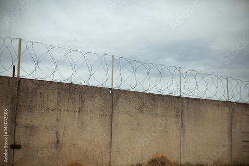 Barbed wire on the fence. A private zone fence. Concrete wall.