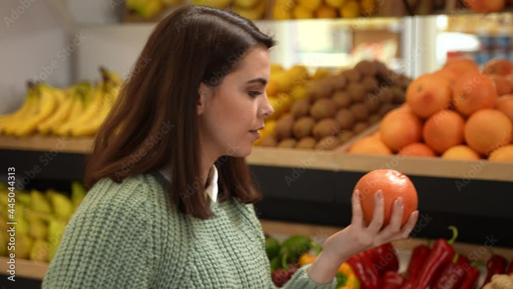 Close-up of health conscious female taking organic citrus fruits while making purchases in supermarket. Vegetarian customer choosing healthy natural products during shopping in farm store