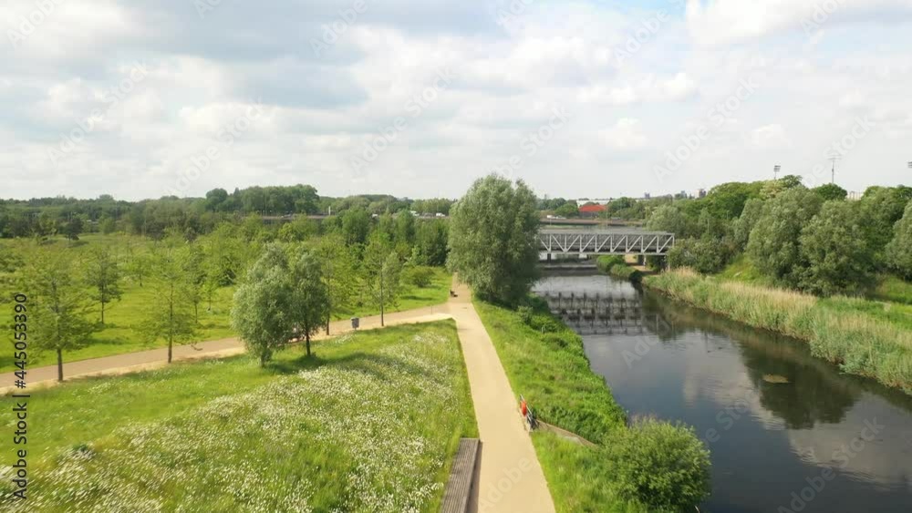 Bridge across river in park, path leading on bank along river Bridge across river in park, path leading on bank along river