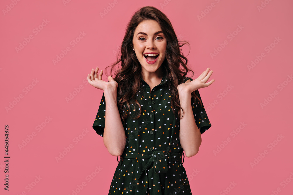 Brunette woman in polka dot dress looks into camera with smile. Beautiful girl feels happy on pink background. Joyful girl in black polka dot dress laughs Brunette woman in polka dot dress looks into camera with smile. Beautiful girl feels happy on pink background. Joyful girl in black polka dot dress laughs