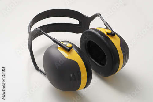 Yellow ear muffs on white desk. Protective headphones. photo
