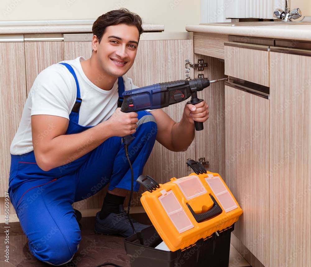 Young repairman working at the kitchen Young repairman working at the kitchen