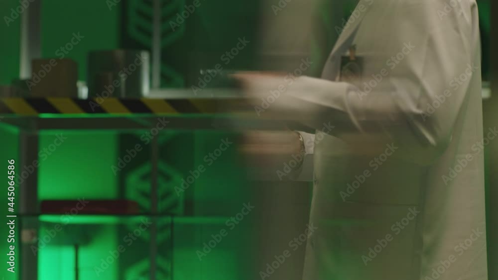 Side unfocused view of male scientist in white uniform holding tablet and working . Man using smart touch screen device in laboratory interior . Lab equipment in background . Slow motion Side unfocused view of male scientist in white uniform holding tablet and working . Man using smart touch screen device in laboratory interior . Lab equipment in background . Slow motion
