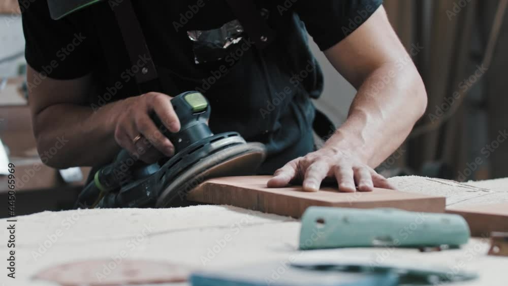 The worker grinding tne angle and the side of a wooden detail The worker grinding tne angle and the side of a wooden detail