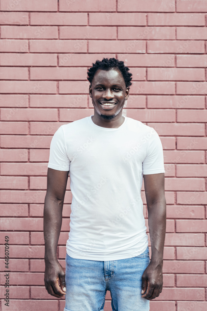 Handsome modern smiling young African man over a pink brick wall Handsome modern smiling young African man over a pink brick wall