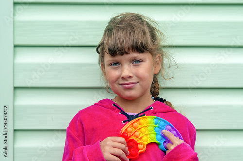 Cute faceless child playing with the Pop It fidget. Selective focus on toy. Push pop bubble flexible fidget sensory toy provide discharge and are good for the development of kid.