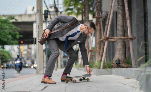 lifestyle businessman in suit riding on skateboard along street photo