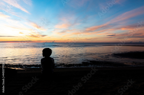 the boy silhouette on a sea beach at sunrise  kid and sea
