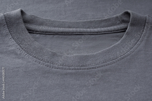 Collar, neck of the T-shirt close-up, copy space, mockup. Ready-made sewn T-shirt made of dark gray thick cotton. Background of natural fabrics, texture. Elements of fashion clothing