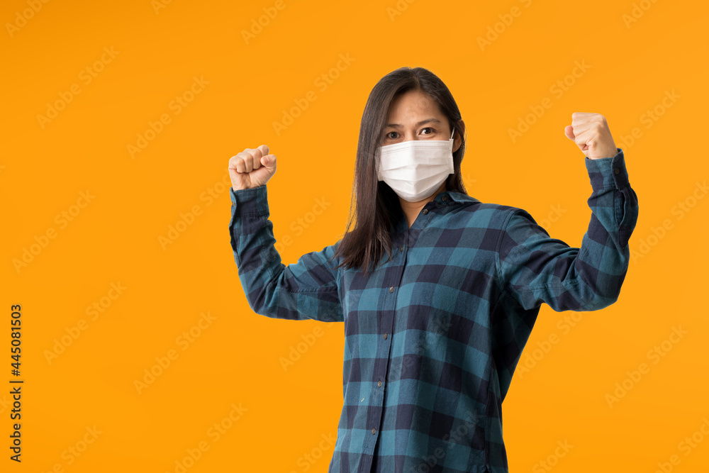 Happy Asian woman wearing hygienic mask to prevent infection corona virus, isolated over yellow background Happy Asian woman wearing hygienic mask to prevent infection corona virus, isolated over yellow background