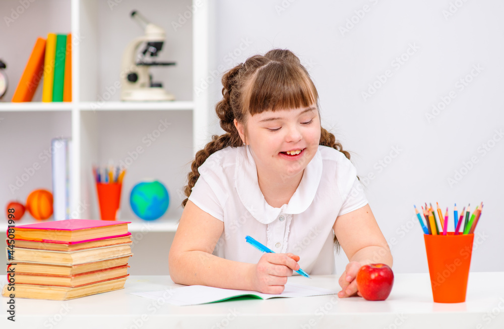 Girl with down syndrome sits at a table at home Girl with down syndrome sits at a table at home