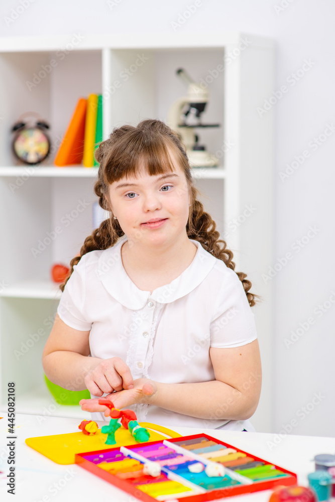 A girl with the syndrome at the table are engaged in creativity. A girl with the syndrome at the table are engaged in creativity.