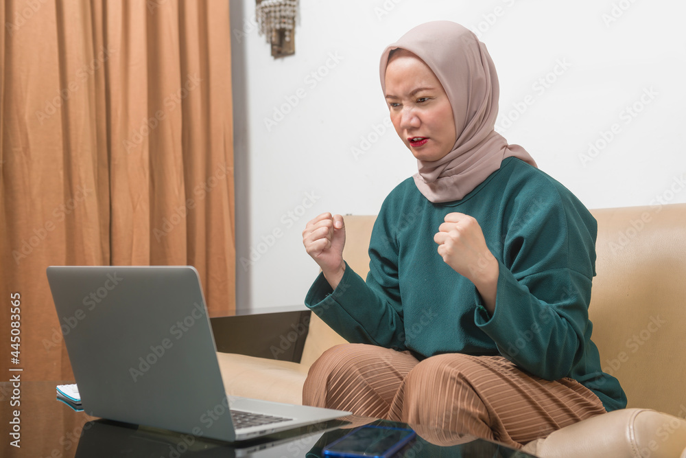 Asian Muslim businesswoman using a laptop working from home Asian Muslim businesswoman using a laptop working from home