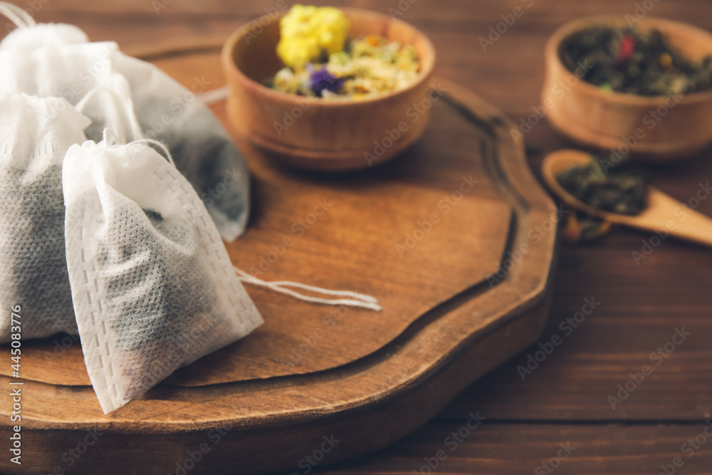 Fototapeta premium Tea bags and bowls with dry leaves on wooden background